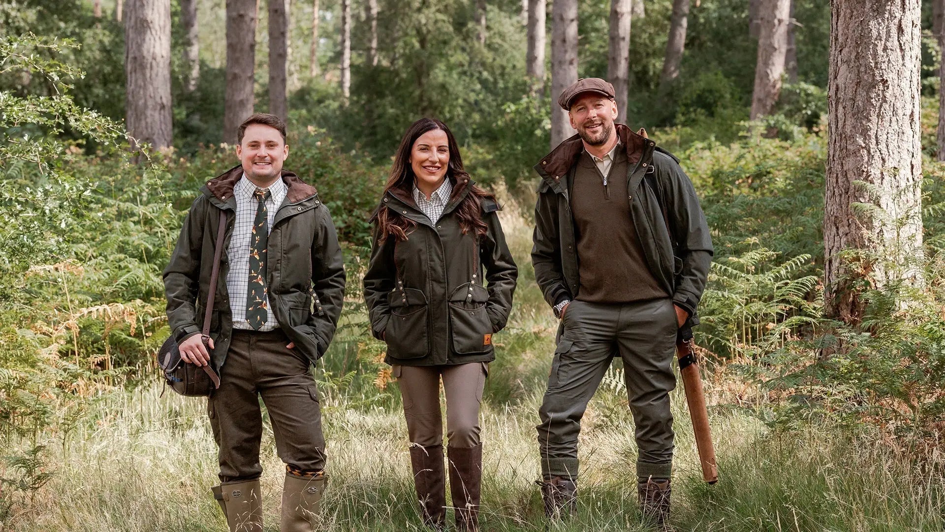 Three people in outdoor hunting gear showing off forest marsh jackets in the woods