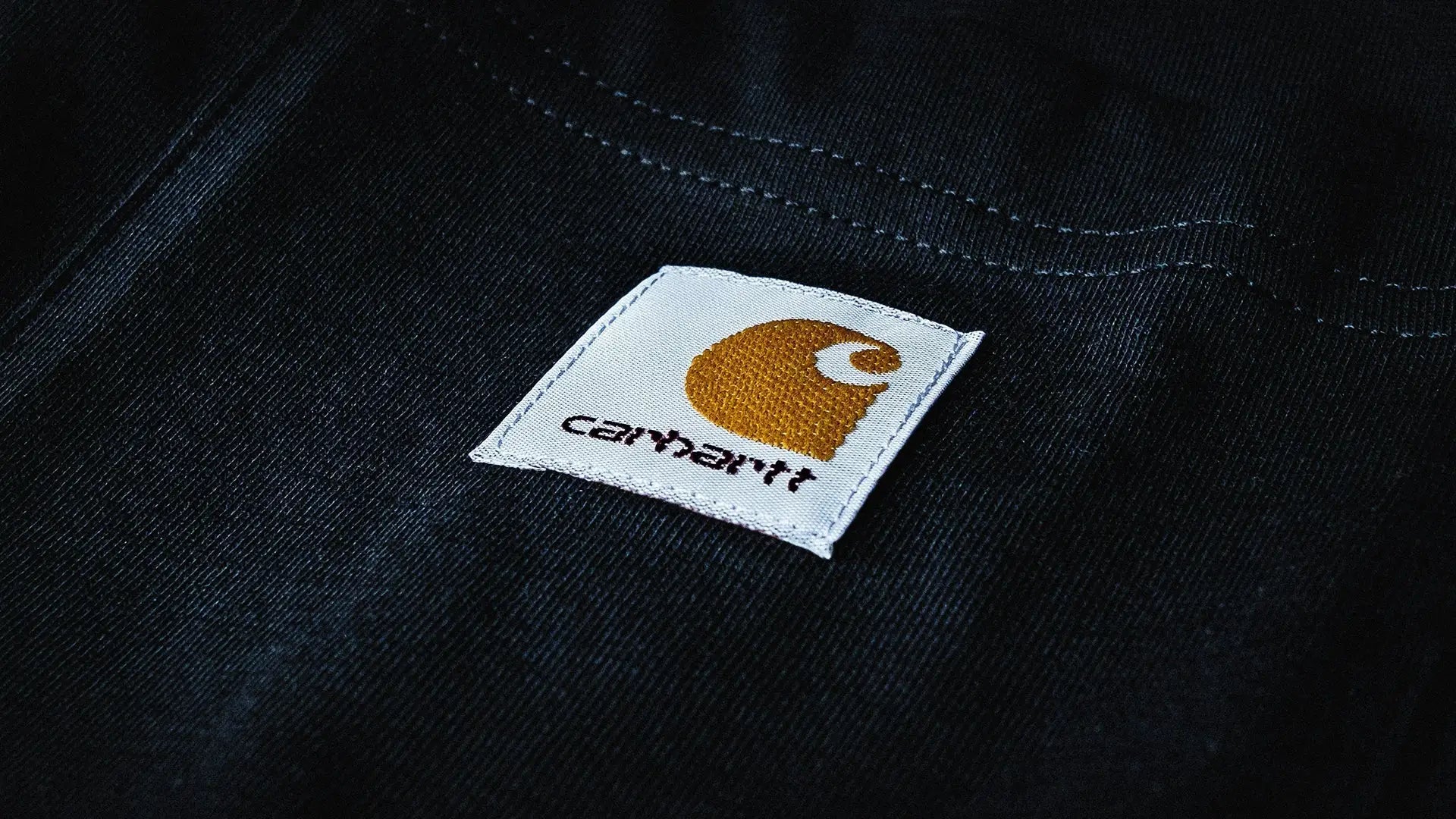 Close-up of black country clothing fabric with Carhartt white and gold label for forest clothing