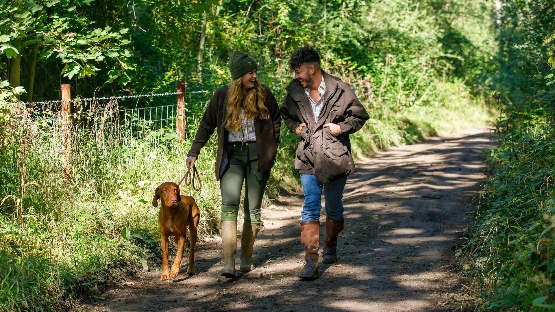 Couple walking a dog in the natural world, showcasing Jack Pyke’s outdoor passion