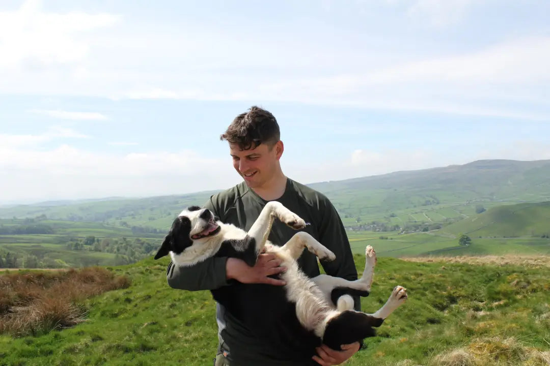 Man holding a dog wearing Bushbuck Apex Crew Base Layer in outdoor gear style
