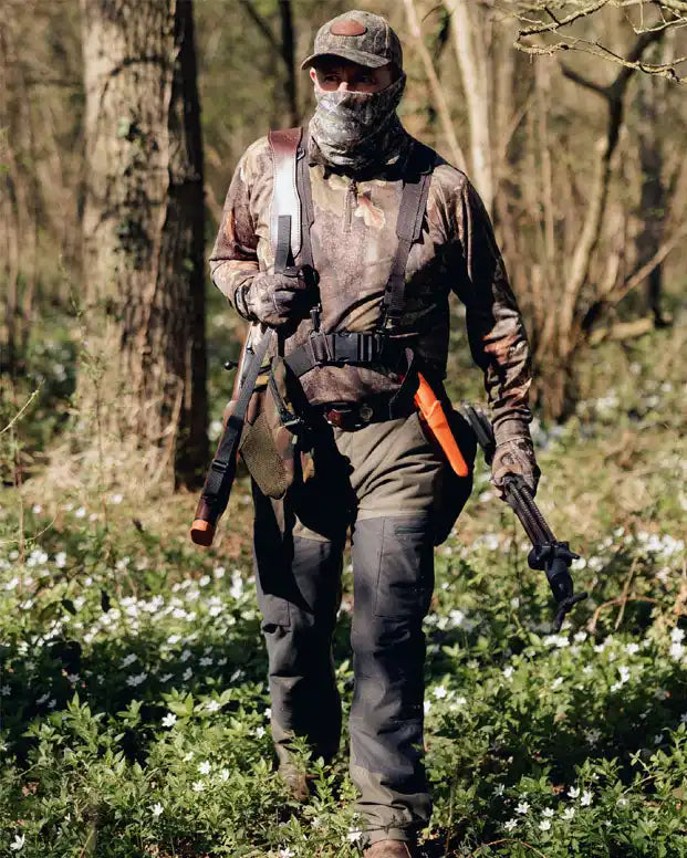 Camo-patterned hunting attire with a rifle, knife, and sling.