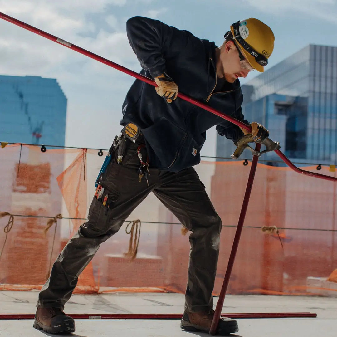 Worker in Carhartt relaxed ripstop cargo pants using red pole tool