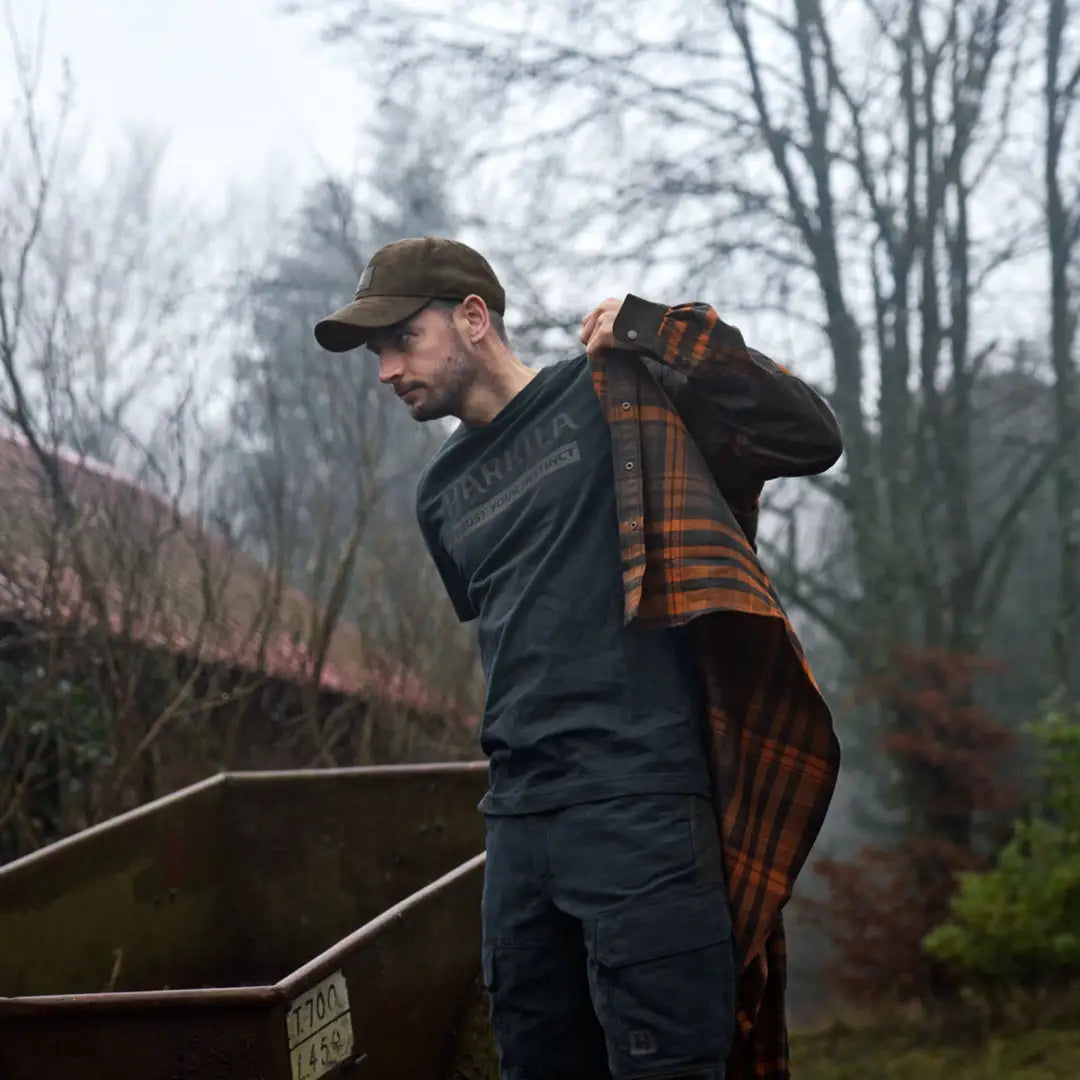 Man wearing härkila logo country clothing hunting plaid shirt in outdoor setting