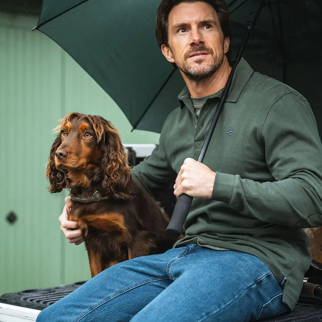 Man and dog under umbrella wearing a Fife Moffat rugby shirt on a rainy day