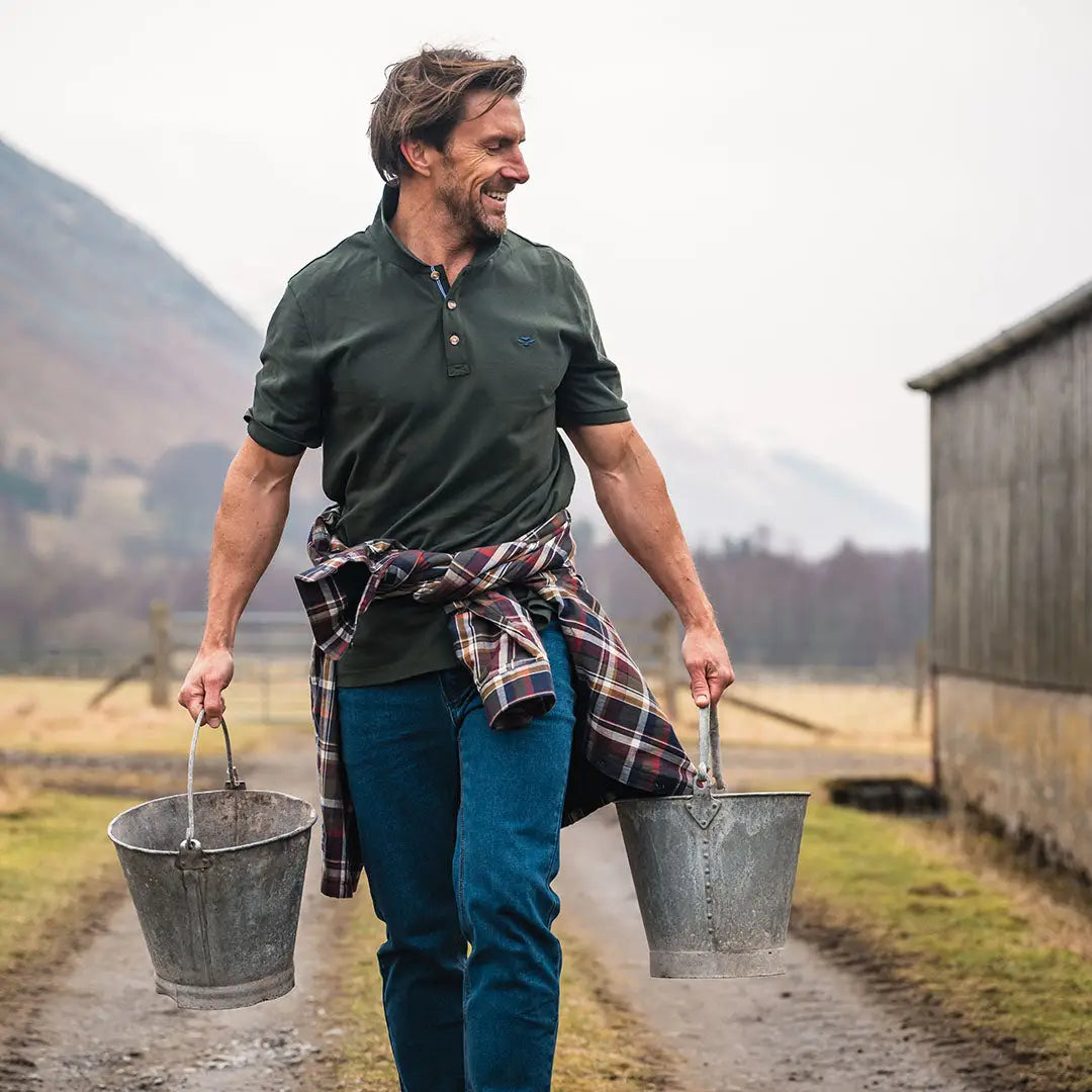 Man carrying buckets while wearing a Fife Newton Pique Polo Shirt