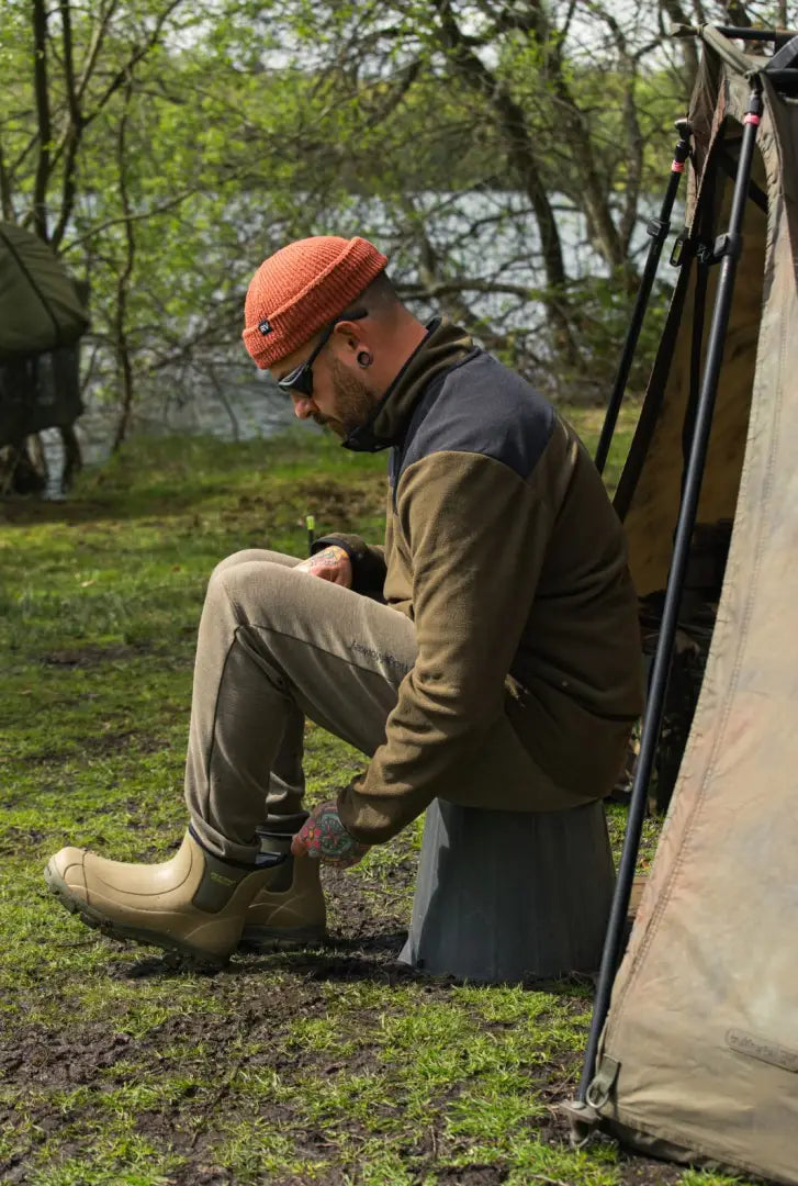 Man in tan boots showcasing Jack Pyke Snap Neck Fleece Top for outdoor style