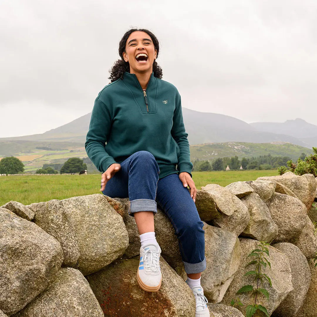 Smiling person in Lighthouse Ladies Coral Jersey, dark teal sweatshirt, blue jeans, sneakers