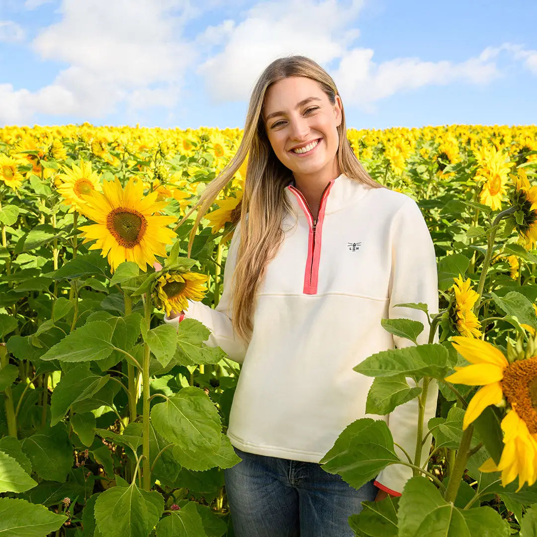 Smiling woman in a sunflower field wearing Lighthouse Ladies Shore II Jersey