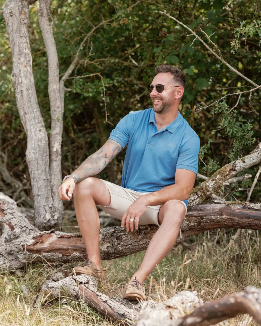 Man wearing New Forest Pique Polo Shirt in blue polo and khaki shorts