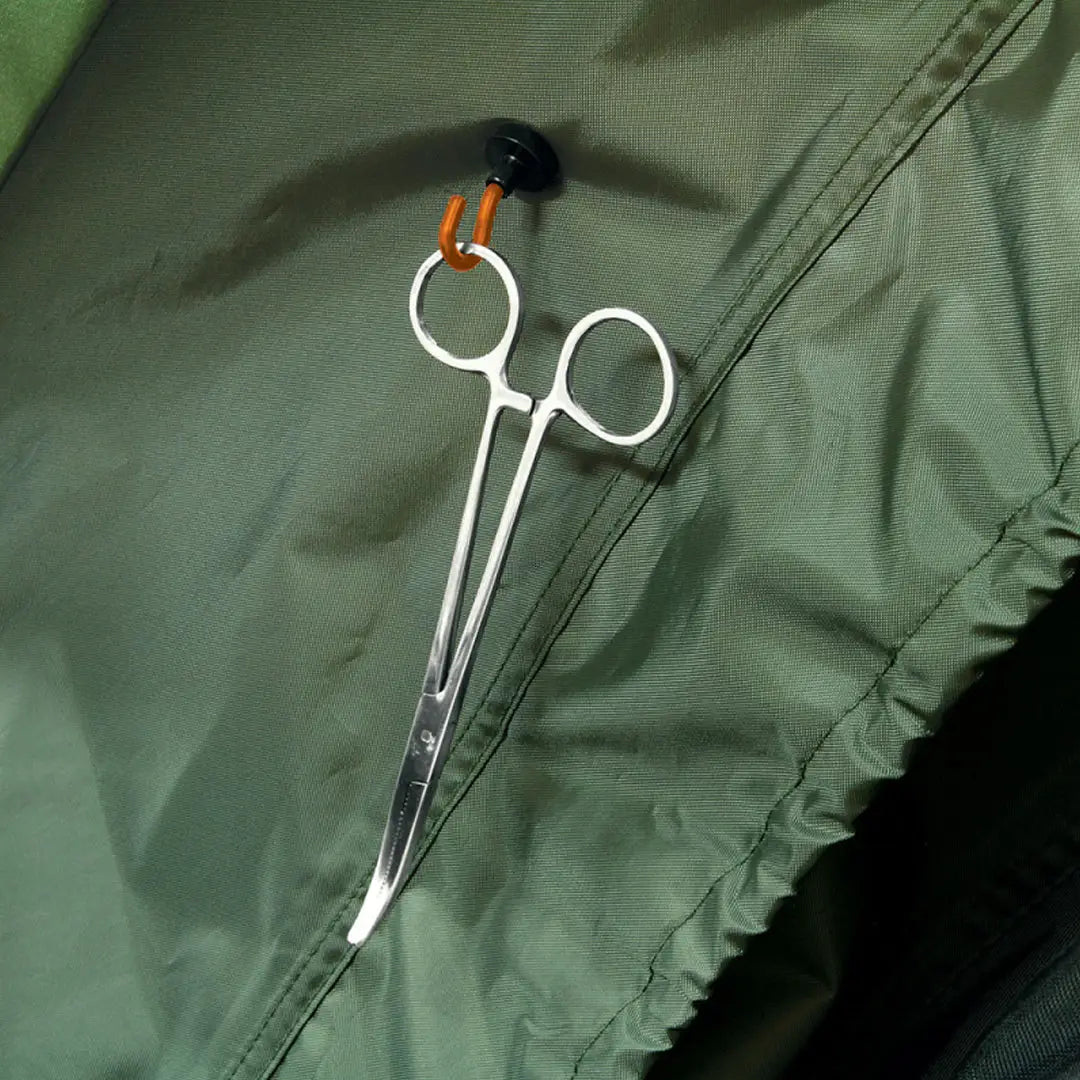 Surgical scissors with orange-tipped handles on green fabric next to super strong bivvy hooks