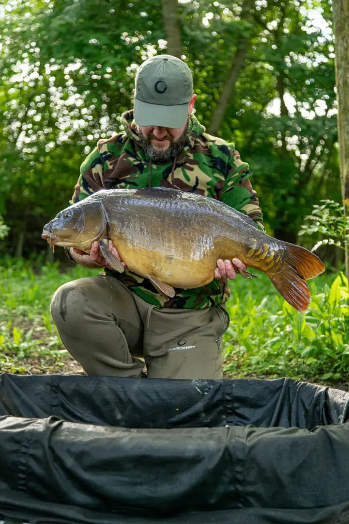 Fisherman proudly holding a large carp while wearing Speero Fleece Hoodie Gen 2