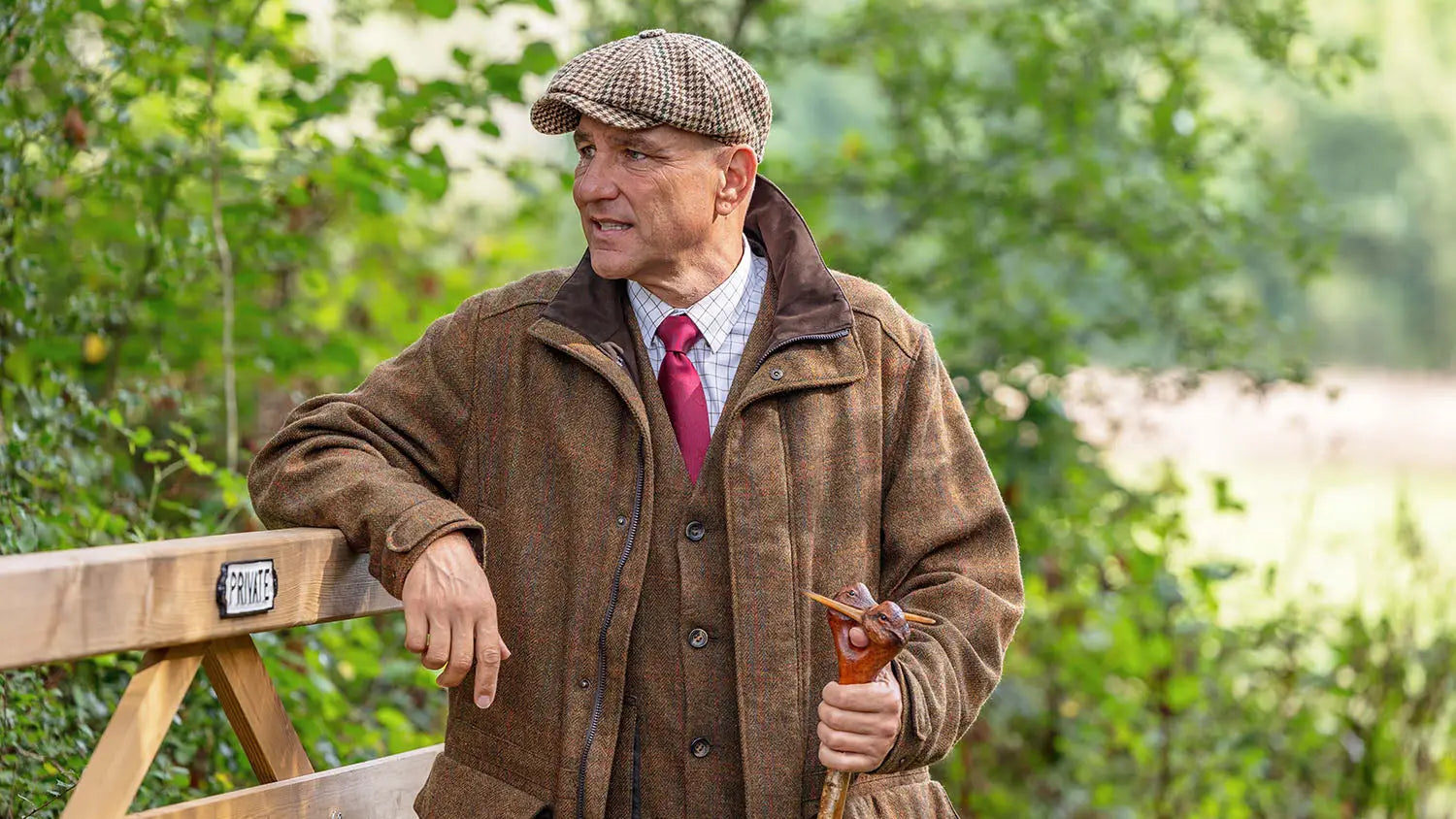 Man in brown tweed jacket and red tie, iconic Härkila outdoor gear for seasoned stalkers