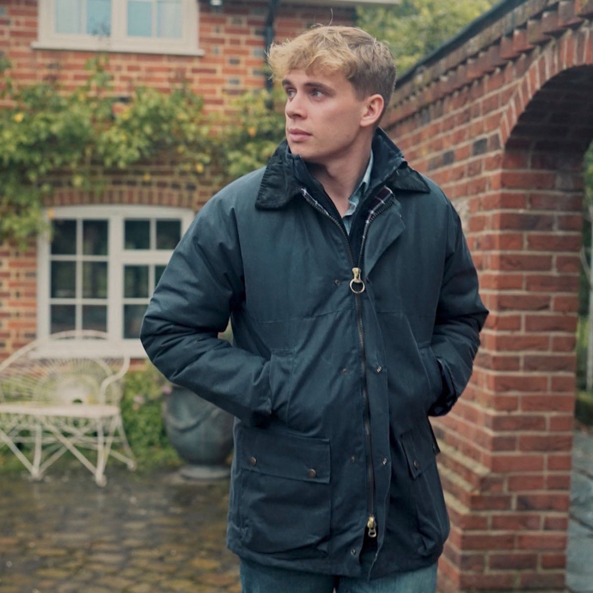 Man wearing a dark jacket standing in front of a brick building