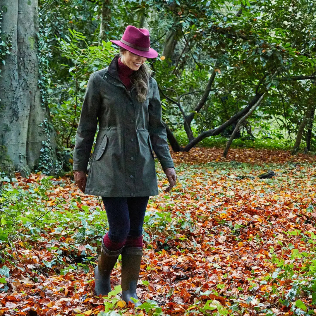 Woman in green coat and purple hat walking through leaves showcasing Alan Paine Dunswell Ladies Jacket