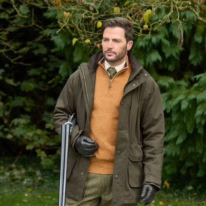 Man in Alan Paine Dunswell field coat with hunting gear and shotgun outdoors