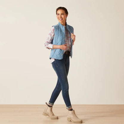 Smiling woman in denim vest and floral shirt showcasing the Ariat Womens Woodside Quilted Gilet