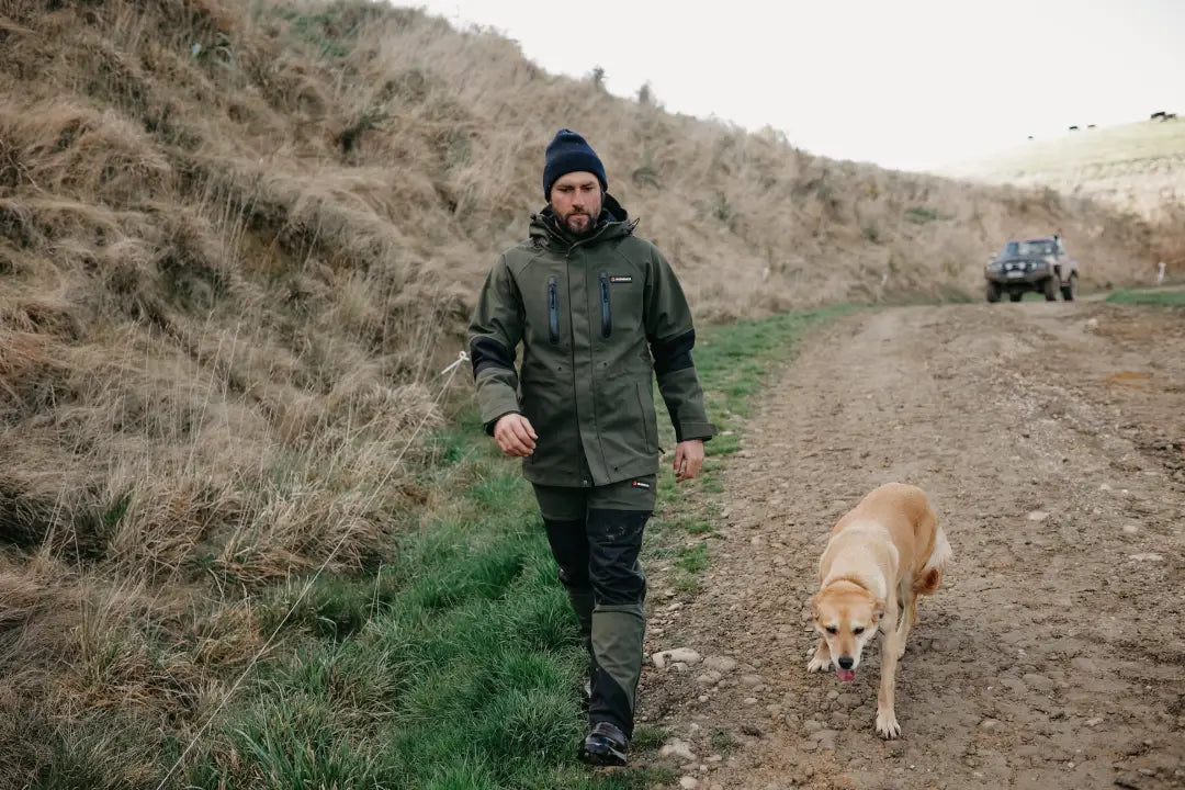 Man in bushbuck defender trousers walking dog in outdoor country gear for hunting and hiking