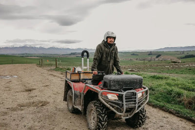 Mud-splattered red ATV with Bushbuck Ranger Bushshirt, perfect for hunting fleece and country clothing