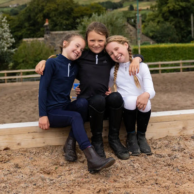 Three young girls in riding attire wearing Cameo Junior Core Baselayer for outdoor fun