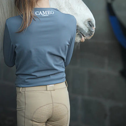 Woman in long-sleeved riding shirt and beige breeches next to horse, perfect country clothing for outdoors