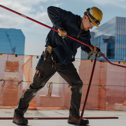 Worker in Carhartt relaxed ripstop cargo pants using red pole tool