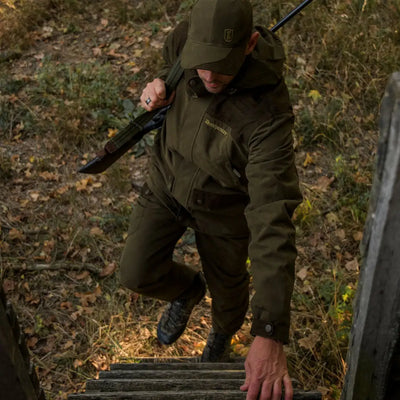 Person in dark green hunting gear climbing a ladder wearing an Eagle Jacket for active hunts