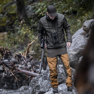 Person in Deerhunter Moor Softshell jacket on rocky terrain with camera tripod