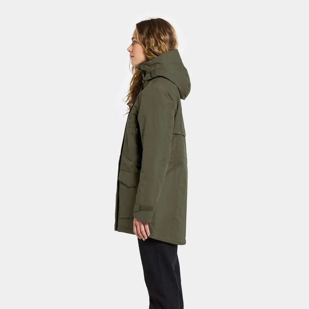 Woman in dark green sporty mid-length parka with large pockets and black pants
