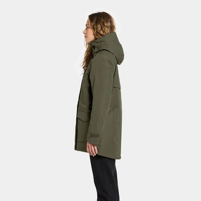 Woman in dark green sporty mid-length parka with large pockets and black pants