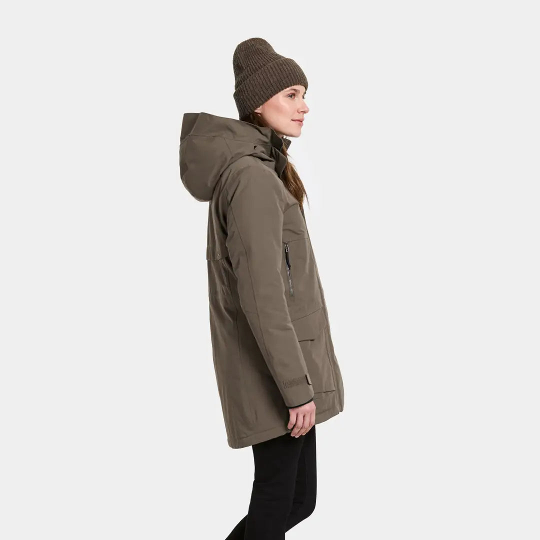 Woman in olive-green sporty mid-length parka and matching knit beanie for Didriksons Frida