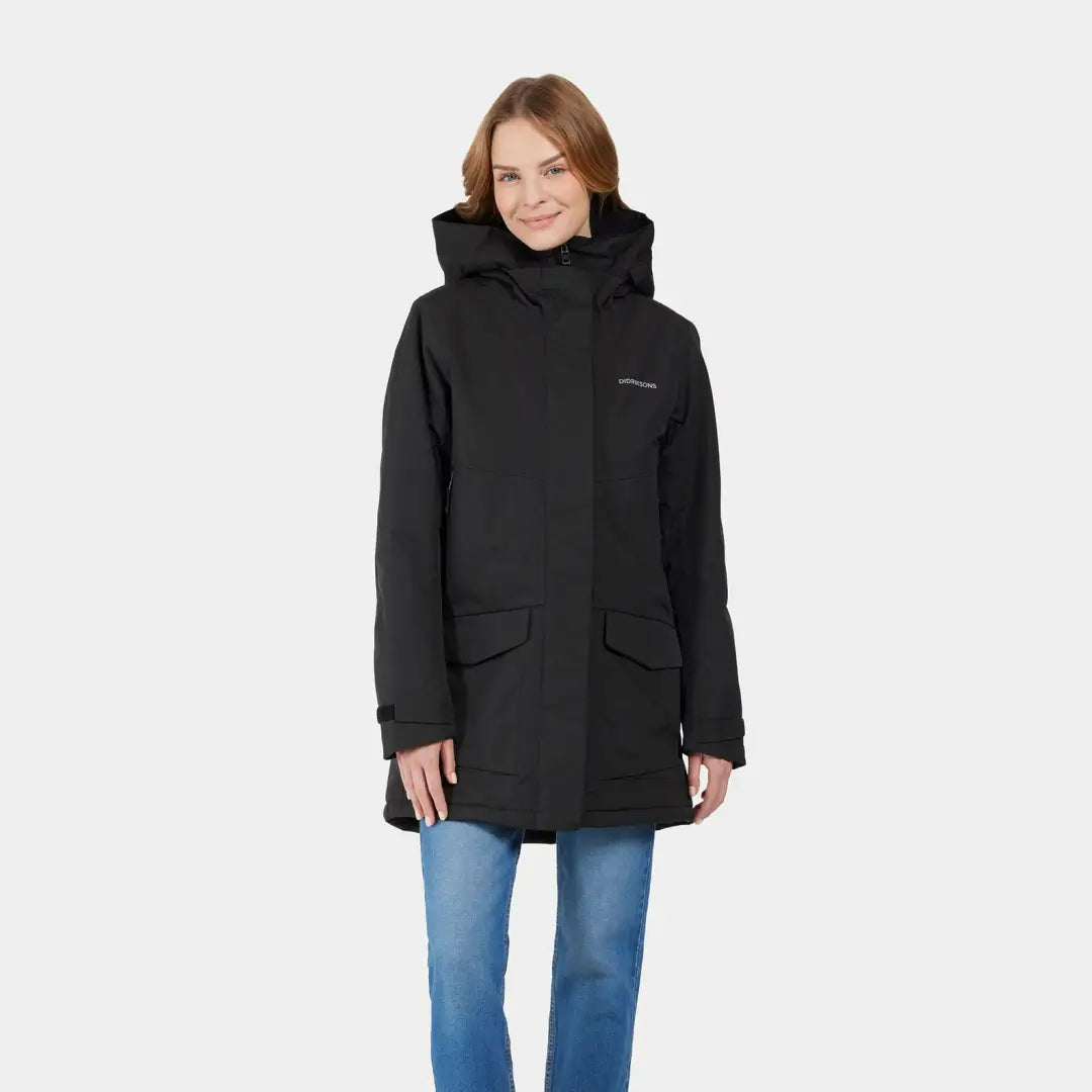 Woman in a black sporty mid-length parka and blue jeans showing Didriksons Frida Womens Parka 7