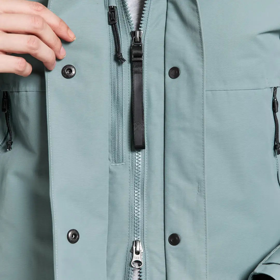 Close-up of Didriksons Frida Womens Parka showing zipper, snap buttons, and hand adjusting it