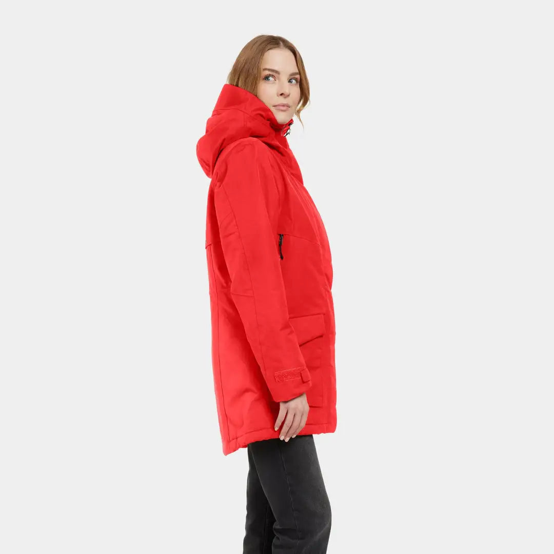 A woman in a sporty mid-length Didriksons Frida Womens Parka with a red hooded style