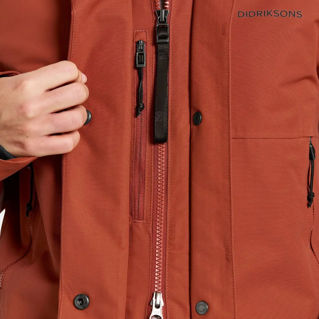 Rust-colored waterproof sporty mid-length parka with zip pockets and snap closures