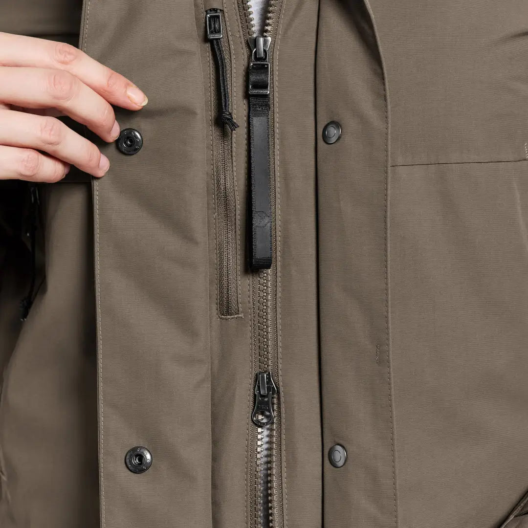 Hands closing the snap on a khaki Didriksons Frida Womens Parka, a sporty mid-length parka