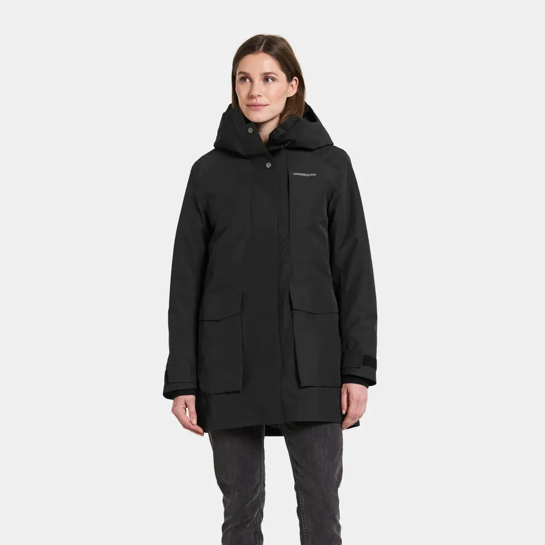 Woman modeling Didriksons Harriet black insulated parka with hood and pockets for country clothing or hunting