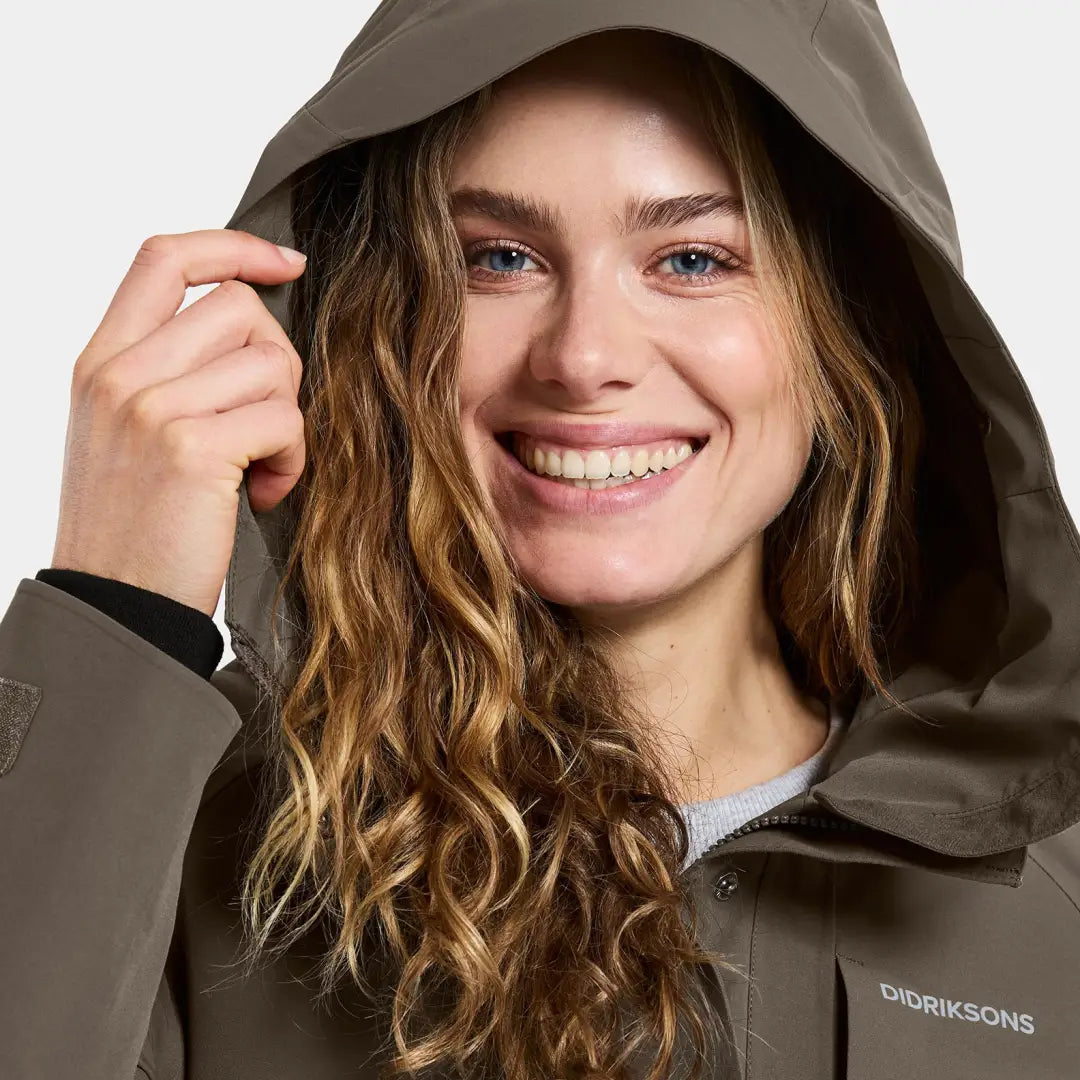 Smiling woman in Didriksons Harriet earth-toned hooded parka, perfect for country hunting