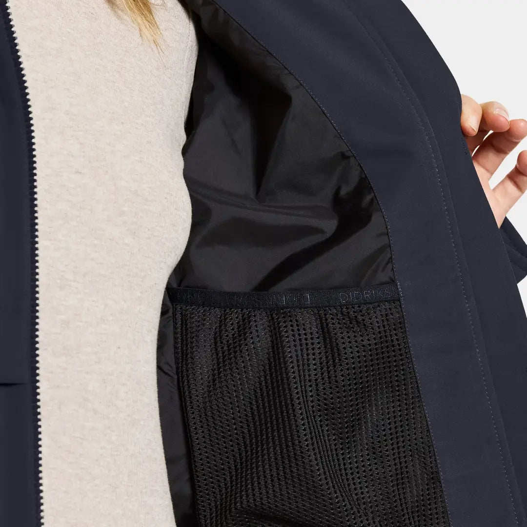 Inside of Didriksons Helle Womens Parka showing navy blue jacket, black mesh pocket, beige undershirt for outdoor country clothing and hunting gear