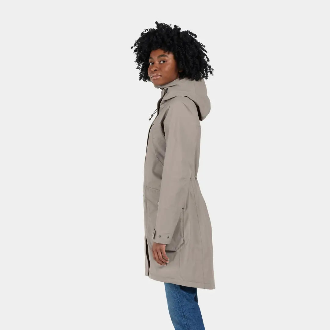 Woman in tan hooded raincoat and blue jeans showcasing Didriksons Thelma Womens Parka
