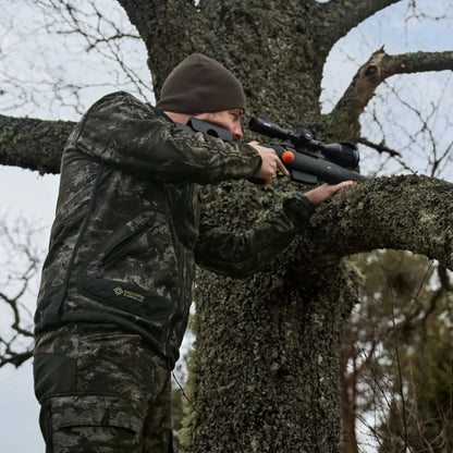 Camouflaged hunter aiming rifle from tree in Härkila Kamko NOCTYX WSP jacket