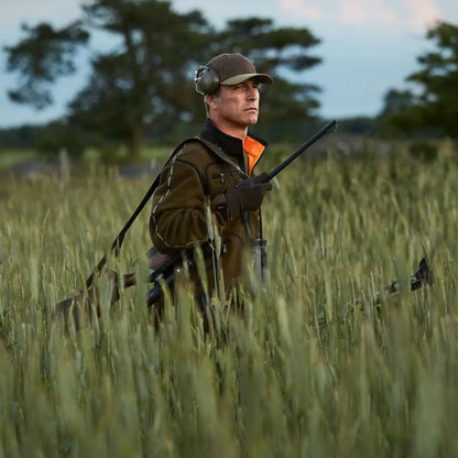 Hunter with shotgun in a field wearing Härkila Kamko Reversible Fleece Jacket for hunting