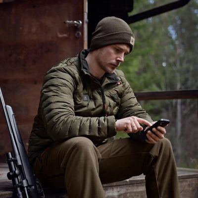 Man in military-style clothing using smartphone while wearing Clim8 Insulated Jacket