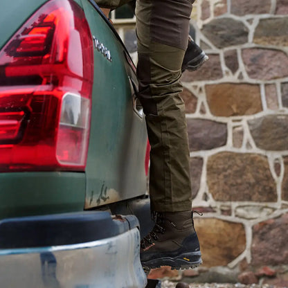 Person climbing into truck bed wearing Harkila Fjell Trousers for country clothing and hunting