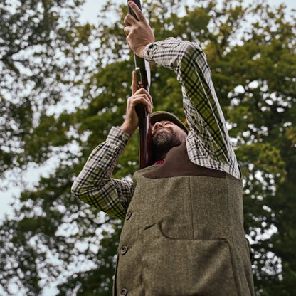 Man holding shotgun wearing Harkila Kenmore Shooting Waistcoat for outdoor shooting