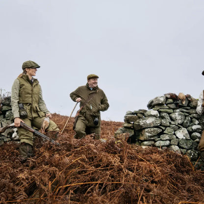 Two men in hunting gear by a stone wall, showcasing the Härkila Kenmore Waistcoat