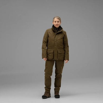 Person in olive green Harkila Retrieve Lady Jacket and pants with a dark scarf