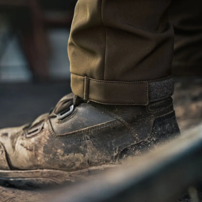 Mud-covered leather boot worn with Härkila Scandinavian Trousers for outdoor adventures