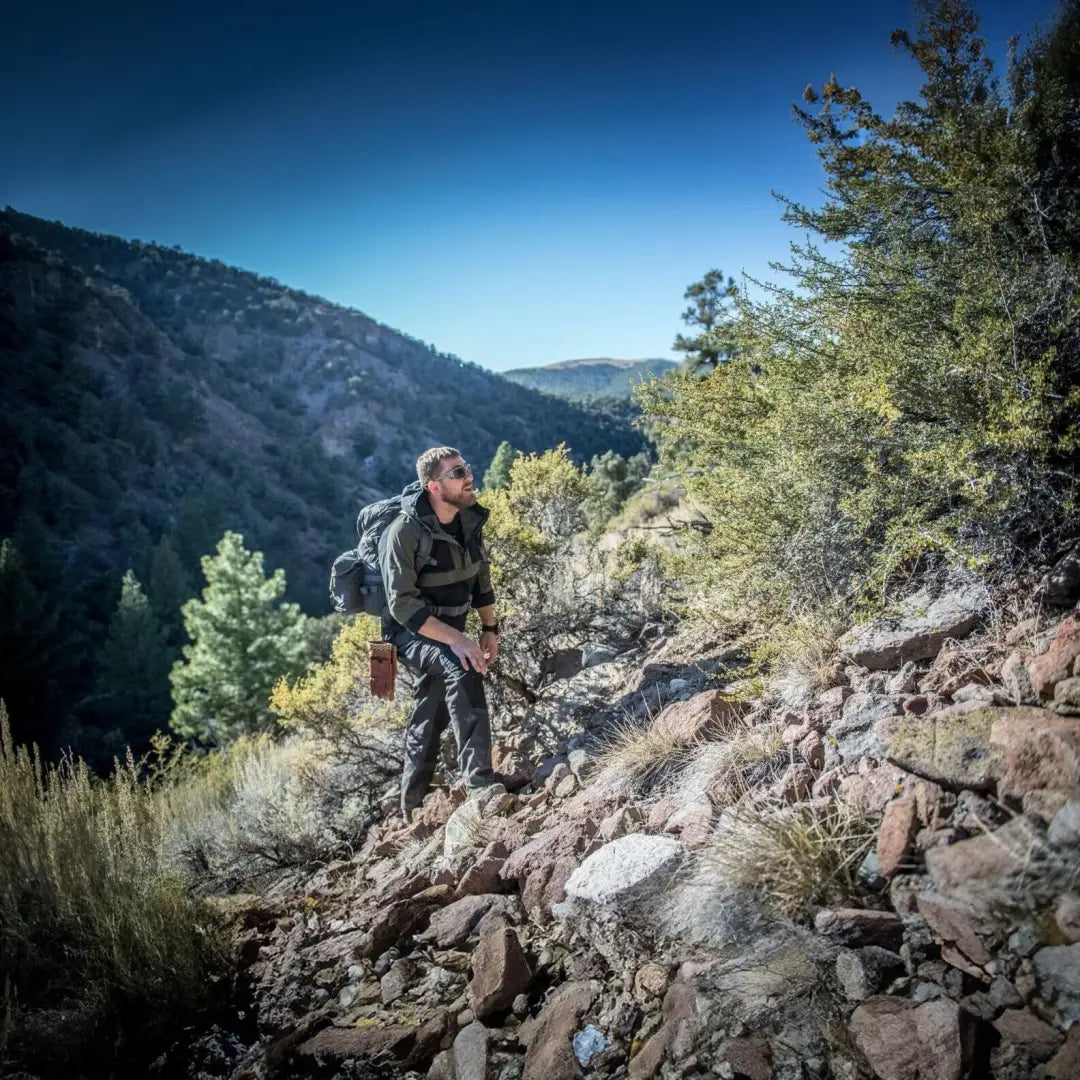 Hiker on a rocky trail wearing a Helikon-Tex Woodsman Anorak Jacket, ready for adventure