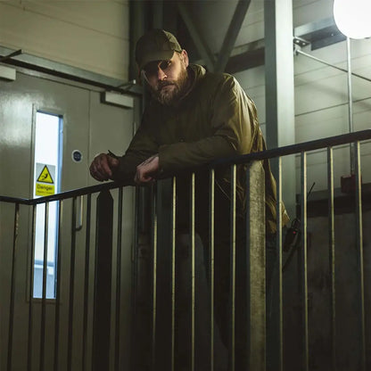 Bearded man in cap wearing Highlander Halo Smock, leaning on a railing