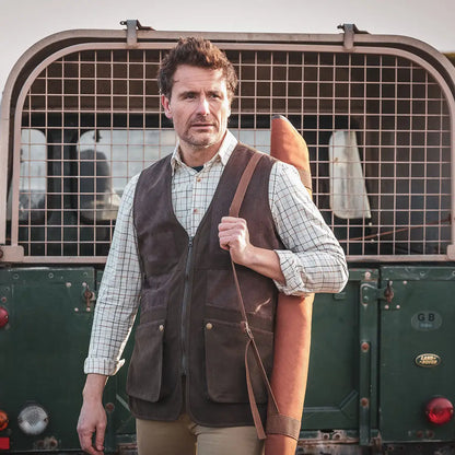 Man in plaid shirt and vest holding rifle case, showcasing Hoggs Of Fife Balmoral Luxury Tattersall Shirt